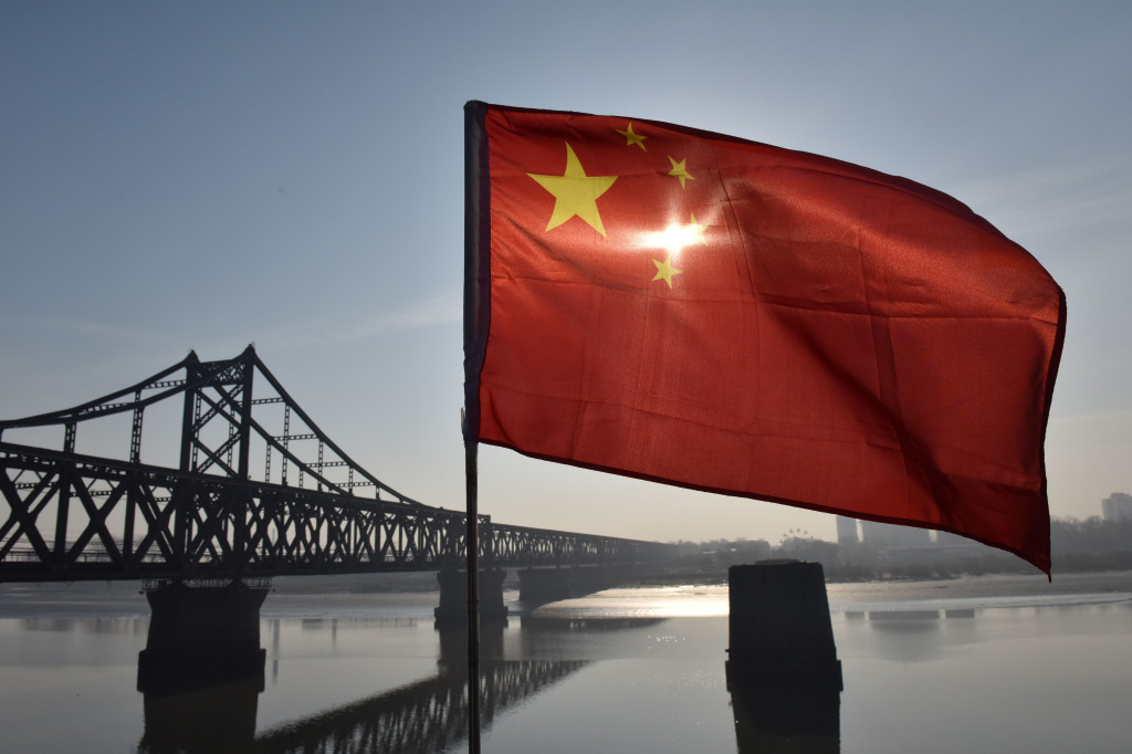 The Chinese flag flies on the Yalu River Broken Bridge, with the Sino-Korean Friendship Bridge, and the North Korean city of Sinuiju behind, in the border city of Dandong, Liaoning province, China on February 23, 2019. (Photo by GREG BAKER / AFP)